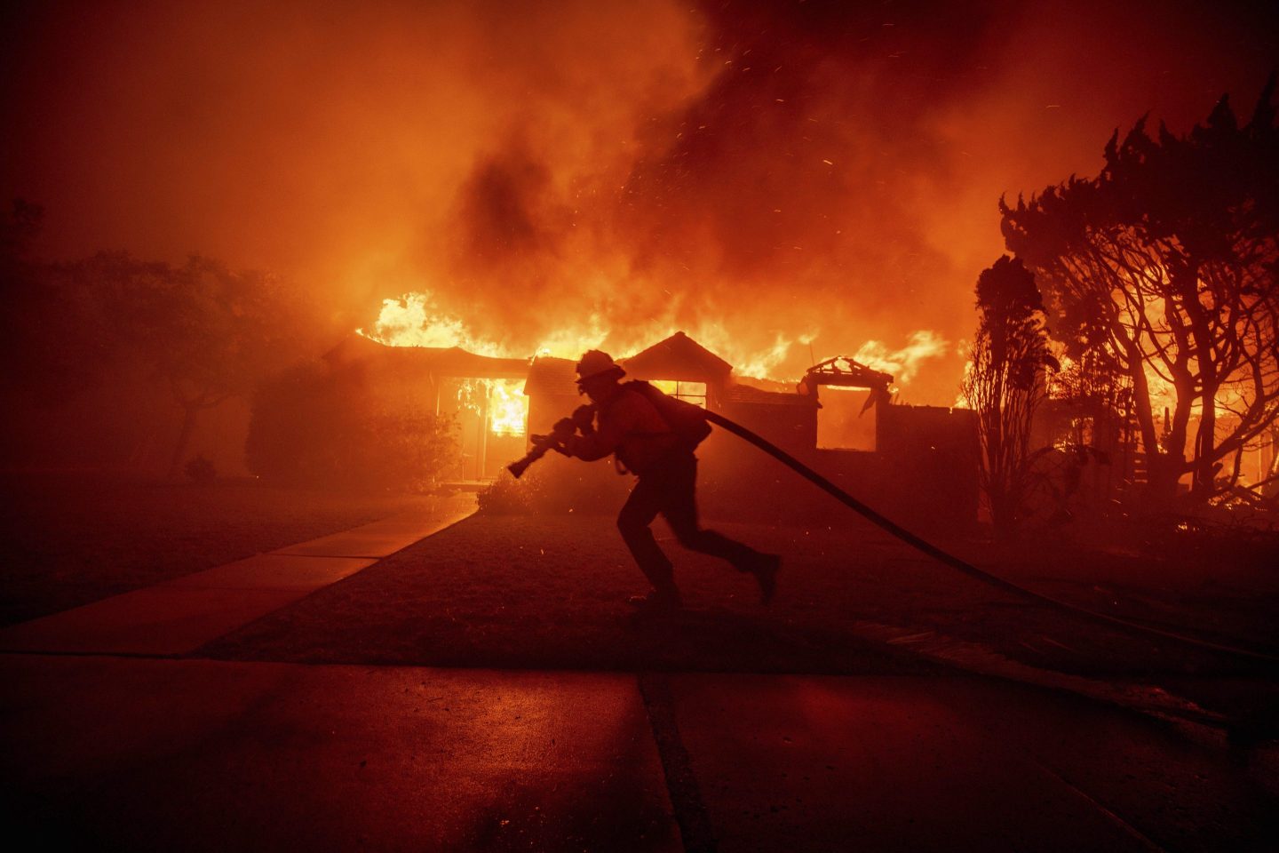 FILE - A firefighter battles the Palisades Fire as it burns a structure in the Pacific Palisades neighborhood of Los Angeles, Jan. 7, 2025. (AP Photo/Ethan Swope, File)